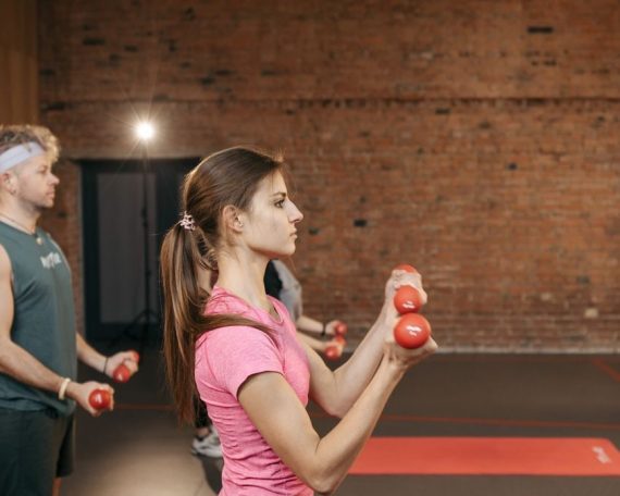 Group of adults exercising indoors with dumbbells, focused on fitness and health.